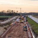 Bodenarbeiten auf der DB-Baustelle auf Fehmarn mit Sonnenuntergang im Hintergrund