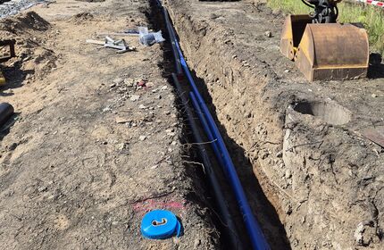 Ein in die Erde gegrabener Kabelschacht mit einer Druckluftleitung