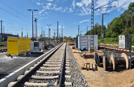 Ein Gleis am Waldrand, rundum Baumaterialien und Container