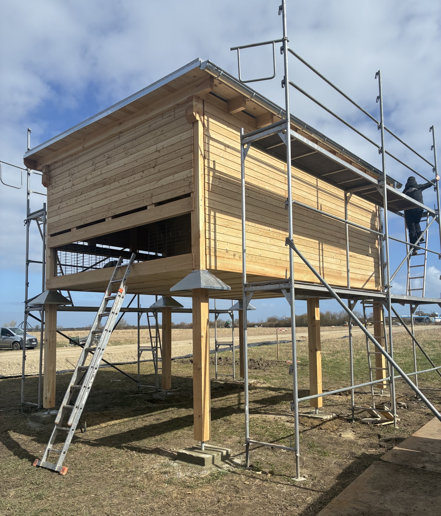 Holzhaus auf Holzbeinen mit Grüst an der Außenwand