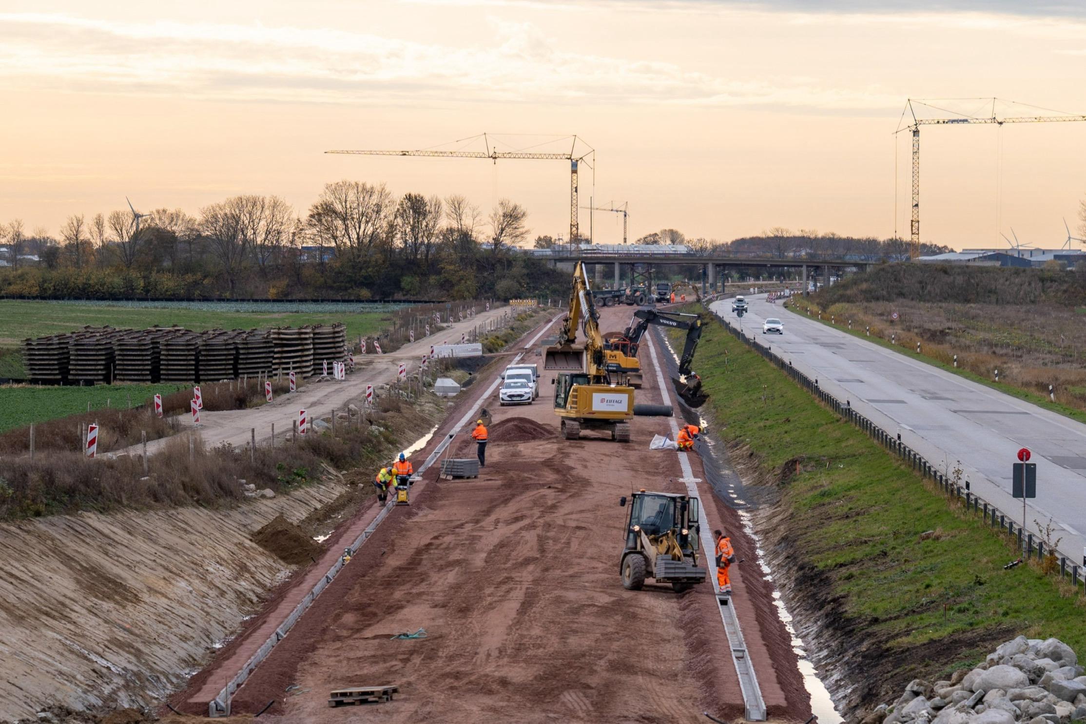 Bodenarbeiten auf der DB-Baustelle auf Fehmarn mit Sonnenuntergang im Hintergrund
