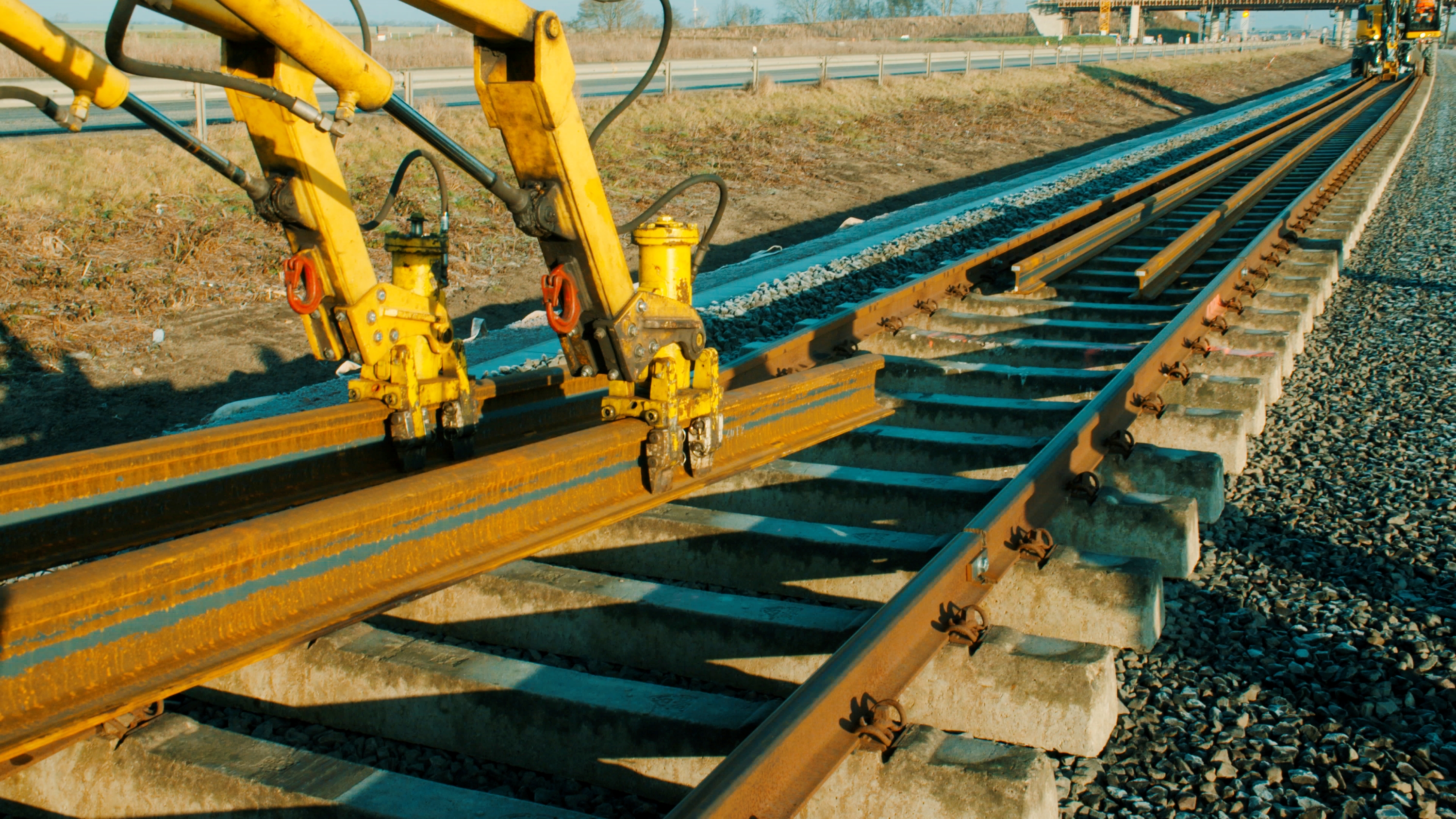 Gelber Greifarm legt Schienen auf einem Gleis ab