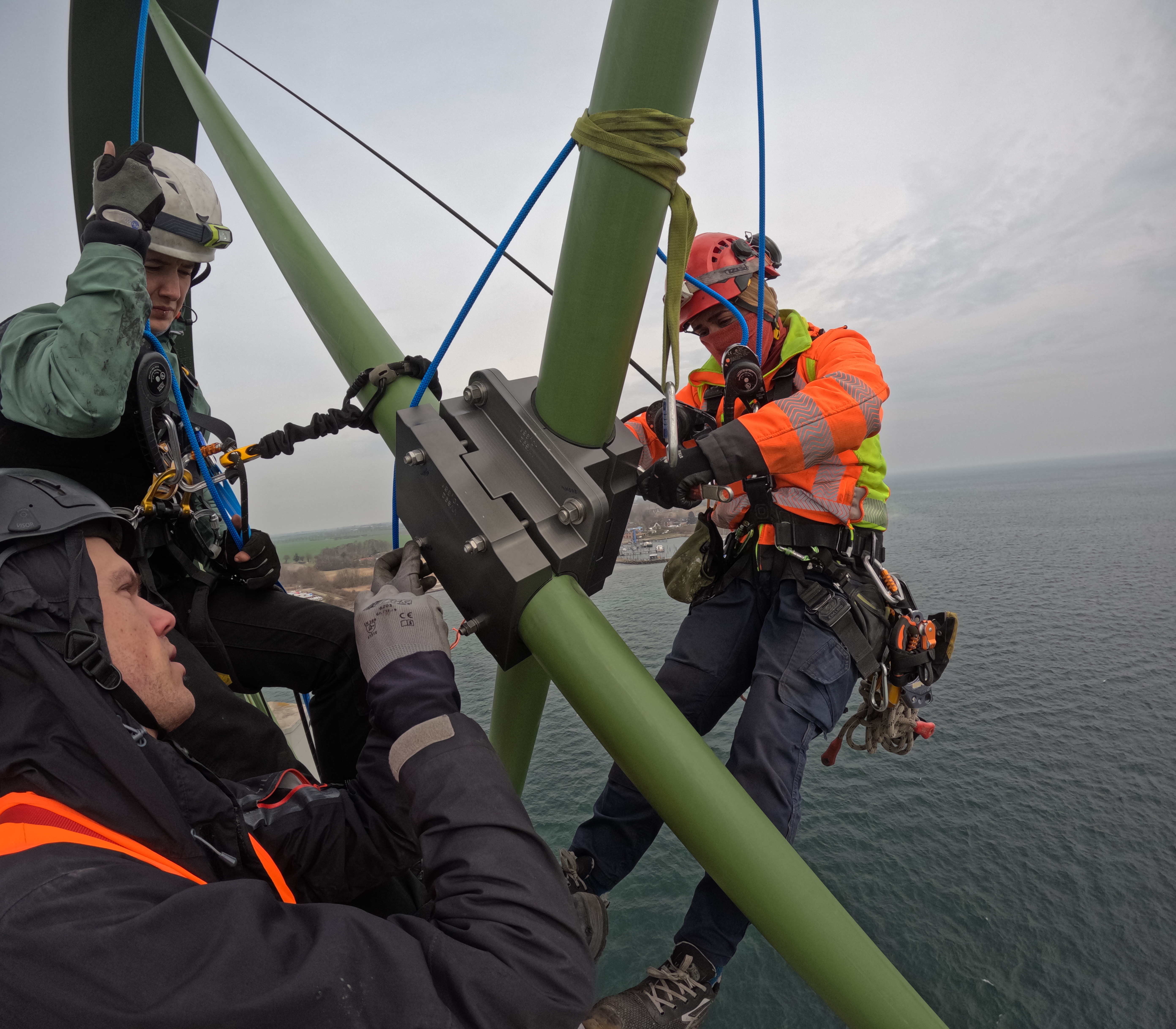 Arbeiter mit Helm und Schutzausrüstung arbeiten an einer Seilklemme an der Fehmarnsundbrücke.