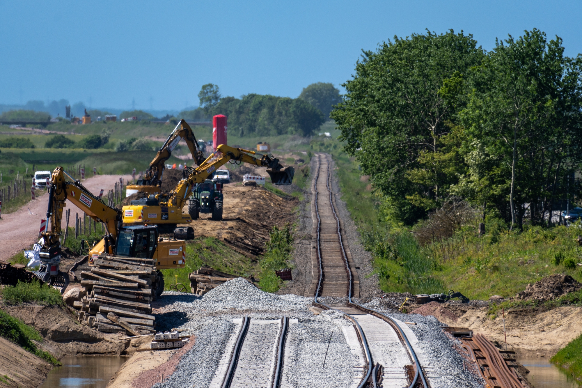 DB-Baustelle auf Fehmarn: vorne zwei neue Gleise, dahinter ein altes. Links der Gleise stehen zwei gelbe Bagger
